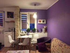Wyjątkowy apartament w sercu Piły في بيوا: غرفة معيشة مع جدران أرجوانية وطاولة وكراسي