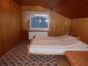 a bed in a wooden room with a window at Apartmány Korenko in Štrba