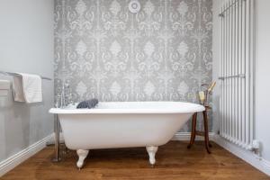 a white bath tub in a bathroom with a wallpaper at The Horseshoe Country Inn in Pickering +91 photos