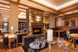 a restaurant with a fireplace and tables and chairs at Villa Beluno Hotel & Spa in San Carlos de Bariloche