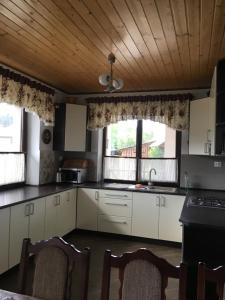 eine Küche mit weißen Schränken und 2 Fenstern in der Unterkunft Карпатский уикенд in Slawske