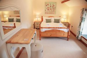 1 dormitorio con cama, mesa y espejo en Cilhendre Holiday Cottages - The Old Cowshed, en Swansea