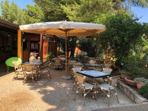 un patio con tavoli, sedie e un ombrellone di Chalet monolocale a Vieste