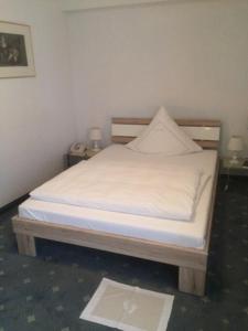a bed with white sheets and a wooden head board at Hotel,Gasthaus zum Wenden in Wendelstein