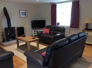 a living room with two leather couches and a fireplace at Brandoch Lodge in Logierait