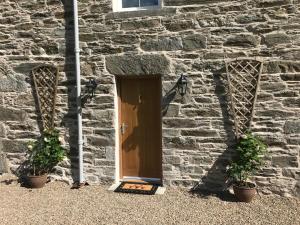 een deur in een bakstenen gebouw met twee potplanten bij Brandoch Lodge in Logierait
