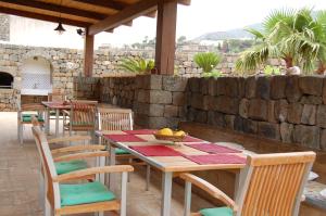einen Tisch und Stühle auf einer Terrasse mit einer Steinmauer in der Unterkunft La Stele di Rekale in Scauri