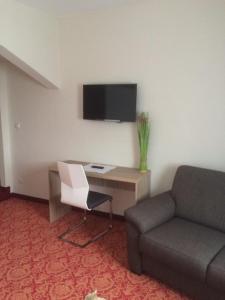 a living room with a couch and a desk and a tv at Hotel,Gasthaus zum Wenden in Wendelstein