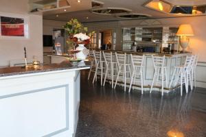 a bar in a restaurant with white stools at Hotel Friesenhof in Norderstedt