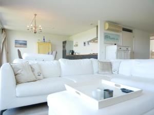 Sala de estar blanca con sofá blanco en Het Strandleven 4, en Goote Keeten