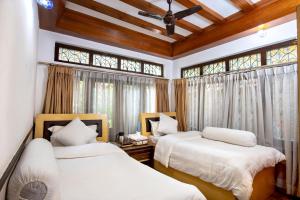 two beds in a room with windows at Shangri-la Boutique Hotel in Kathmandu