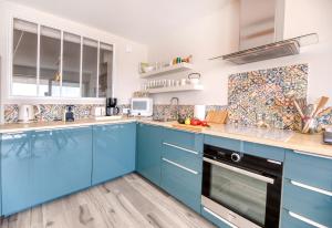 een blauwe keuken met witte muren en houten vloeren bij Face à la mer - Première conciergerie in Palavas-les-Flots