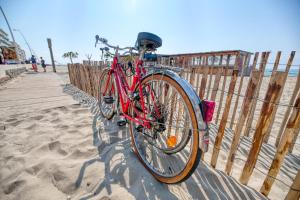 un vélo rouge enchaîné à une clôture sur la plage dans l'établissement Face à la mer - Première conciergerie, à Palavas-les-Flots