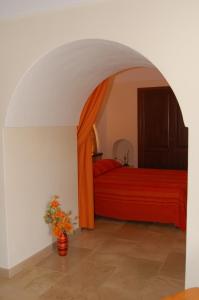 Un dormitorio con una cama roja y un jarrón de flores en La Stele di Rekale, en Scauri