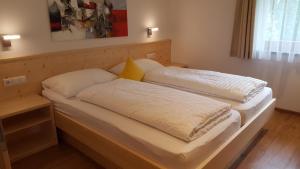 two beds with white sheets and yellow pillows at Residence Klementhof in Natz-Schabs