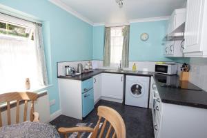 a blue kitchen with a washing machine in it at Penrose Bed & Breakfast in Lostwithiel