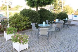 eine Gruppe von Tischen und Stühlen auf einer Terrasse mit Blumen in der Unterkunft Hotel Friesenhof in Norderstedt