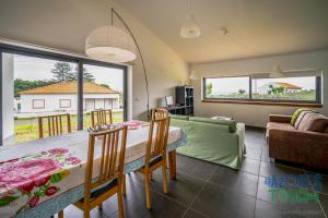 a dining room with a table and chairs and a couch at Casa da Barra in Santa Cruz da Graciosa