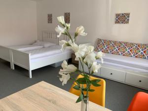 a room with two beds and a table with a vase with flowers at Mikulov Inn - Apartments Slunce in Mikulov