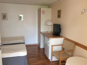 MörbylångaにあるKalkstenens Bed and Breakfastのベッド、デスク、テレビが備わる小さな客室です。
