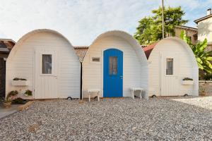 two white sheds with a blue door and two benches at Le botti di Agorà in Negrar