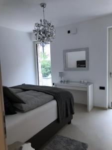 a white bedroom with a bed and a mirror at Le Rocce in Torri del Benaco