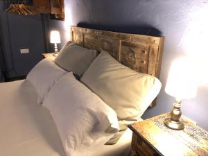 a bed with white pillows and a wooden headboard at La Torre Del Angel Casa Rural in Mirambel