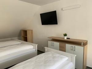 a room with two beds and a tv on the wall at Mikulov Inn - Apartments Slunce in Mikulov