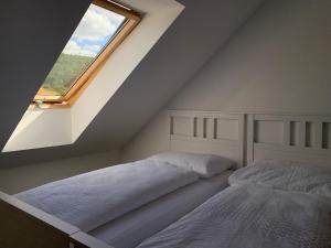 two beds in a attic bedroom with a window at Mikulov Inn - Apartments Slunce in Mikulov