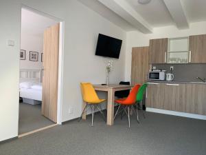 a room with a table with four chairs and a kitchen at Mikulov Inn - Apartments Slunce in Mikulov