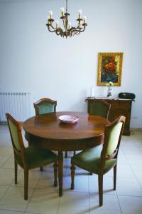 einen Esstisch mit grünen Stühlen und einem Kronleuchter in der Unterkunft LE GINESTRE in Sulmona