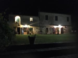 une maison éclairée la nuit dans la cour dans l'établissement La Canonica Di San Michele, à Monteriggioni