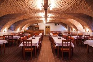 una sala da pranzo con tavoli bianchi e sedie in legno di Hotel Pod Sluncem a Třebíz