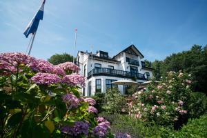 een wit huis met een vlag en bloemen bij Boutique hotel Puur Zee - Adults Only in Wijk aan Zee