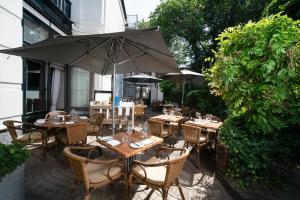 un restaurant en plein air avec des tables, des chaises et un parasol dans l'établissement Boutique hotel Puur Zee - Adults Only, à Wijk aan Zee