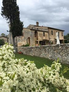 Cette maison ancienne est dotée d'un mur en pierre et de fleurs blanches. dans l'établissement La Canonica Di San Michele, à Monteriggioni