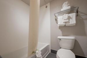 a bathroom with a toilet and a tub and towels at Stratford House Inn in Edmond