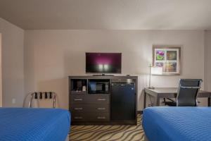 a hotel room with two beds and a flat screen tv at Stratford House Inn in Edmond