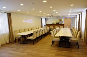 une salle de conférence avec des tables et des chaises blanches dans l'établissement Pasažo namai B&B, à Raseiniai