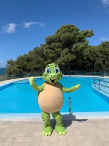 a frog mascot standing in front of a pool at Hotel Pinija in Petrcane