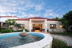 a house with a fountain in front of a building at Nostos Hotel in Afitos