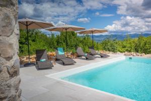 a swimming pool with chairs and umbrellas next to a pool at Vila na Kamenu in Dobrinj