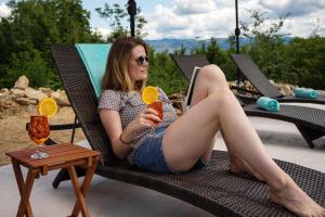 a woman sitting in a chair holding a drink at Vila na Kamenu in Dobrinj