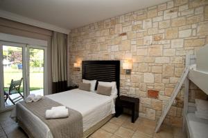 a bedroom with a bed and a stone wall at Nostos Hotel in Afitos