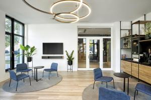 uma sala de estar com cadeiras azuis e um lustre em H.ome Serviced Apartments München em Munique