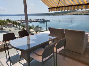 een tafel en stoelen op een patio met uitzicht op het water bij Luxury apartment by the sea with private whirlpool and terrace 50m2 in Posedarje