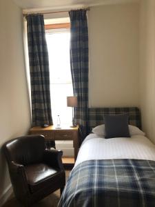 a bedroom with a bed and a chair and a window at Redcliffe Hotel in Inverness