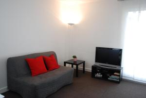 ein Wohnzimmer mit einem Stuhl und einem TV in der Unterkunft Appartements Paris Boulogne in Boulogne-Billancourt