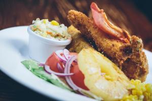 a plate with fried fish and vegetables and a side of coleslaw at Kellys Inn in Garvaghy