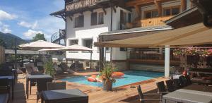 a swimming pool with tables and umbrellas next to a building at Hôtel Le Sporting in Morzine